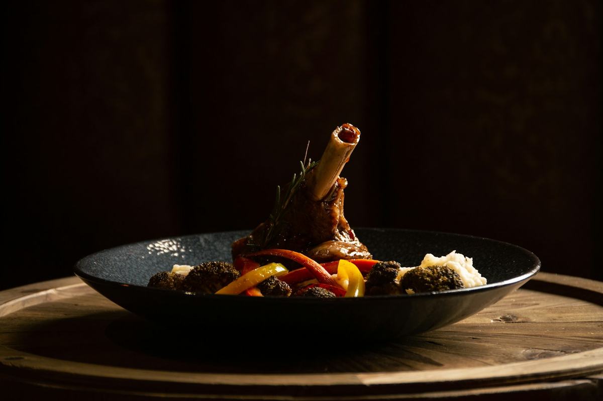Lamb shank from the oven in a dark bowl