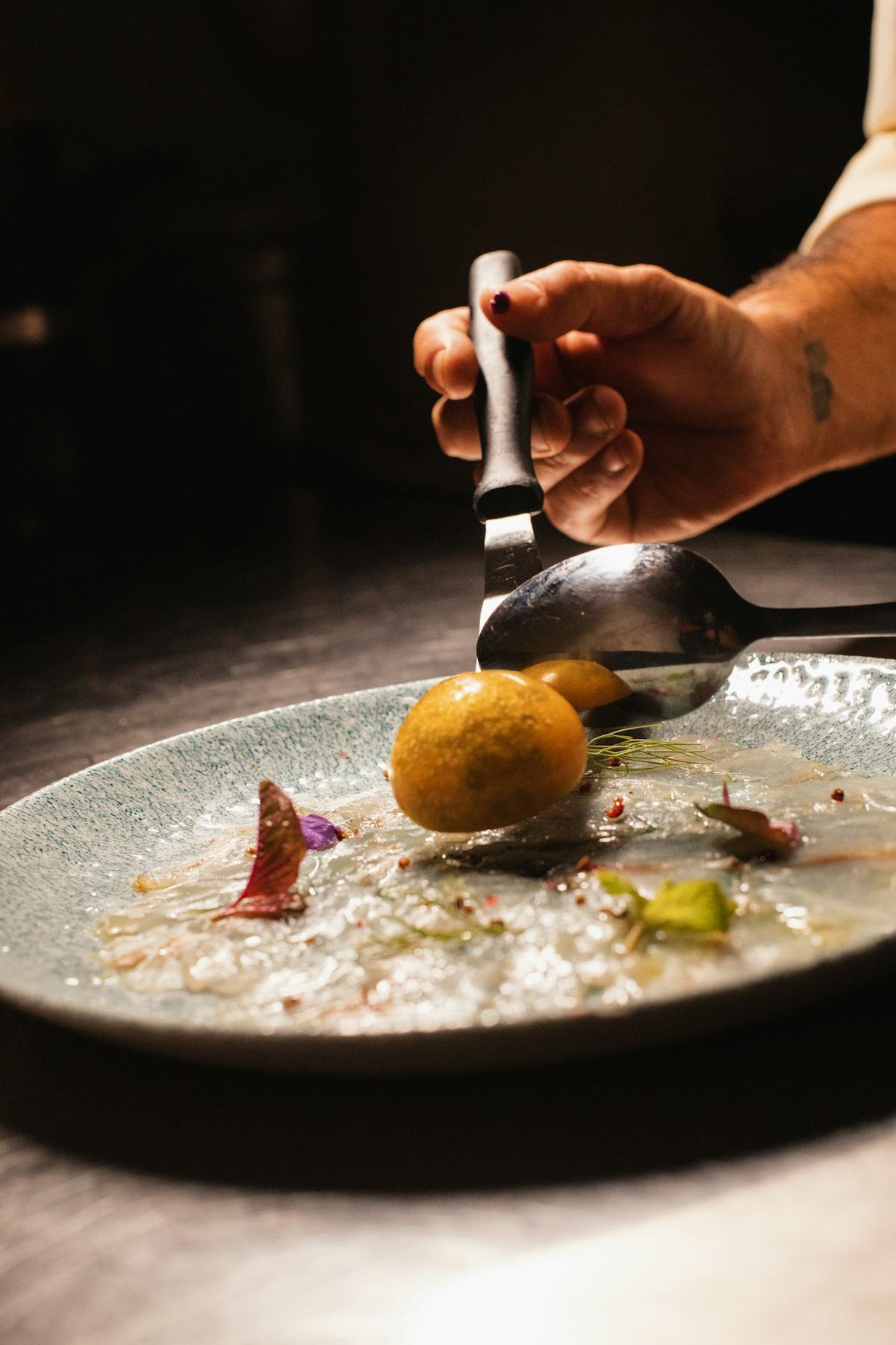 A cook finishing a plate at the pass